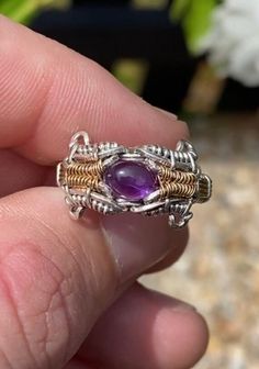 This size 7 ring features a stunning amethyst and peridot gemstone with an intricate pattern woven along the band. Spun in .925 silver and 14k yellow gold fill wire. Includes complimentary polishing pad and gift box. Spiritual Gemstone Ring, Bohemian Sterling Silver Wire Wrapped Jewelry, Bohemian Wire Wrapped Jewelry For Anniversary, Hand Wrapped Metal Jewelry For Healing, Unique Hand Wrapped Jewelry For Anniversary, Hand Wrapped Spiritual Jewelry For Anniversary, Spiritual Hand Wrapped Jewelry For Anniversary, Unique Gemstone Jewelry For Healing, Artisan Purple Gemstone Jewelry