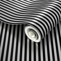 a black and white striped wallpaper with a rolled up roll on the floor next to it