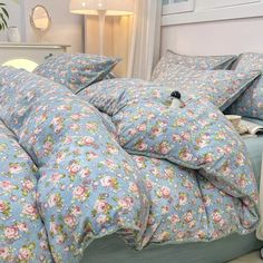 a bed with blue and pink flowers on it in a bedroom next to a lamp