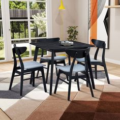 a dining room table with four chairs and a rug on the floor in front of it