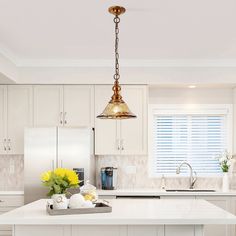 a kitchen with white cabinets and yellow flowers on the counter top, along with an island in the middle