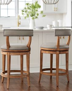 two wooden barstools with grey upholstered backrests in a white kitchen