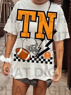 a girl wearing a tennessee football t - shirt in front of a brick building with her hand on her hip