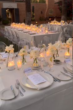 the tables are set with white flowers and candles