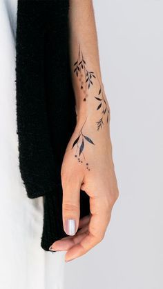 a woman's hand with a small tattoo on her left wrist and the other arm