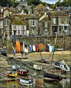 there are many surfboards in the water and on the shore, with houses in the background