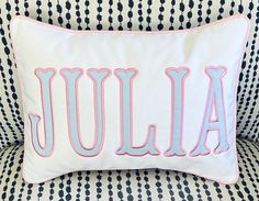 a pillow with the word julia on it sitting on a couch in front of a black and white polka dot pattern