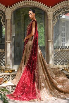 A gold tissue lehnga and choli features detailed zardoze and resham embroidery and is paired with a contrasting crimson cotton net dupatta adorned with gold zardoze borders and sequins. Gold Intricate Embroidered Raw Silk Sharara, Gold Sharara In Raw Silk With Intricate Embroidery, Gold Raw Silk Sharara With Intricate Embroidery, Designer Gold Anarkali Set With Intricate Embroidery, Designer Gold Raw Silk Lehenga, Gold Jamawar Anarkali Set With Intricate Embroidery, Gold Anarkali Choli In Raw Silk, Gold Raw Silk Lehenga With Dupatta, Gold Lehenga With Dupatta In Raw Silk