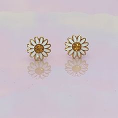 "Daisy stud earrings are so cute for the flower child! Hard enamel in bright white & yellow accented with polished gold. Wildflower + Co. ♥ Measures approx. ¼ \" ♥ Materials: dipped in gold plating, glitter flooded resin, & enamel. Posts are titanium - good for sensitive ears! ♥ Packaged in our cute gift box ♥ Designed by & exclusive to Wildflower + Co. ♥ Imported ♥ Product safety - intended for use by adults only; CA residents - see shop policies for Prop 65 warning ♥ Includes 1 pai Gold Cottagecore, Cottagecore Earrings, Earrings White Gold, Daisy Studs, Earrings Aesthetic, Gift Box Design, Cute Gift Boxes, Daisy Earrings, Earrings Flower