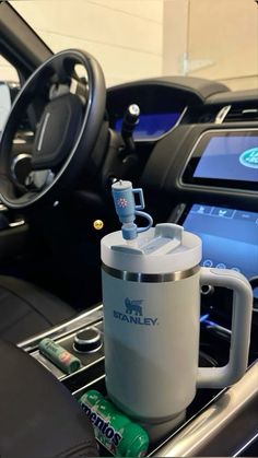 the interior of a car with an electronic device and drink holder on the dash board