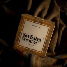 a box of sweater weather sitting on top of a plaid blanket with the label over it