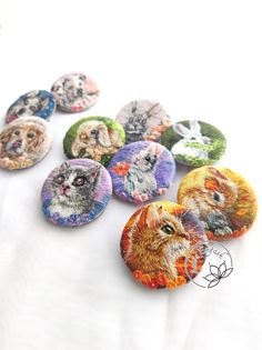 a bunch of buttons that are sitting on a white tablecloth with the faces of cats and dogs painted on them