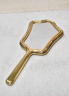 a gold plated mirror sitting on top of a white counter next to a tile floor