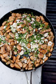 a skillet filled with lots of food on top of a white countertop next to a wall