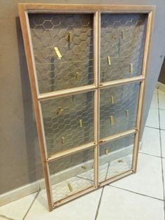 a chicken wire and wood display case in the corner of a room with tile flooring