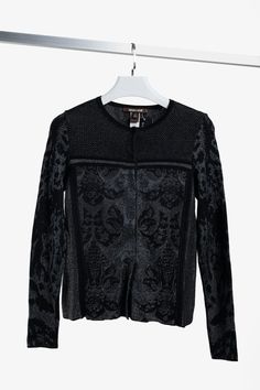 An elegant black knit sweater jacket from Italian designer Roberto Cavalli woven from a viscose/wool blend featuring black ribbing interspersed with metallic-silver and grey threading. This cardigan has a round neckline, long sleeves, a concealed snap button front closure, and a glimmering pattern reminiscent of baroque patterning.  Size: IT 42  Condition: Pristine; no visible signs of wear  Approximate Measurements (Laid Flat):  Shoulder: 16.25" (41.5 cm)  Chest: 12.75" (32.5 cm) Sleeve: 24.5" (62.5 cm) Length down back: 22.5" (57 cm)  Composition: 53% viscose, 49% wool, 7% polyester Black Jacquard Knit Cardigan, Elegant Black Jacquard Knit Sweater, Elegant Jacquard Knit Cardigan For Work, Elegant Jacquard Knit Sweater, Elegant Black Fine Knit Cardigan, Elegant Knit Outerwear, Elegant Fitted Fine Knit Outerwear, Elegant Jacquard Knit Winter Outerwear, Elegant Fitted Jacquard Knit Cardigan