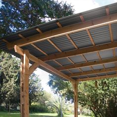 a covered patio area with benches and trees in the background at an outdoor space that is well maintained