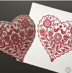 two red and white paper cut out to look like hearts with flowers in the middle