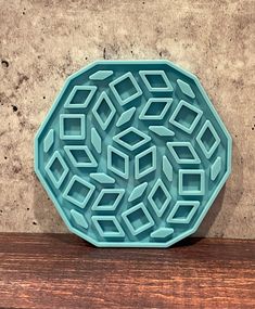 a blue plate sitting on top of a wooden table next to a wall and floor