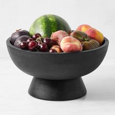 a black bowl filled with fruit on top of a table