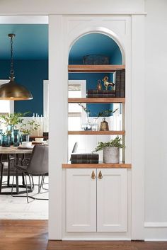 an open door leading to a dining room with blue walls and white cabinets, wood floors