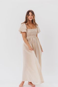 Be the life of the party in the Nan Maxi Dress! This beautiful gown comes in a gorgeous, multi-season neutral hue, and features a smocked bodice and puffed sleeves that can be worn on or off the shoulder - it's like getting two dresses in one! Style the Nan with slides for a casual, feminine outfit, or with neutral heels for the perfect event dress. FIT: Runs true to size. MATERIAL: GARMENT DETAILS: Neutral maxi dress with empire waist silhouette, smocked bodice, and puffed sleeves with elastica Chic Beige Maxi Dress With Smocked Bodice, Beige Feminine Maxi Dress With Smocked Bodice, Feminine Beige Maxi Dress With Smocked Bodice, Chic Beige Smocked Dress With Smocked Bodice, Beige Maxi Dress With Smocked Bodice And Midi Length, Spring Dresses With Elastic Sleeves For Gatherings, Spring Midi Dress With Fitted Bodice And Bishop Sleeves, Fitted Smocked Dress With Ruched Bodice For Brunch, Flowy Smocked Dress With Puff Sleeves