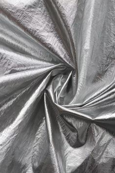 a silver metallic fabric is shown in close up, as if it's going to fall