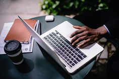 a man is typing on his laptop while sitting at a table with a coffee cup