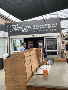 two men standing in front of a building with boxes stacked on top of it and the words thank you for supporting our family - owned business