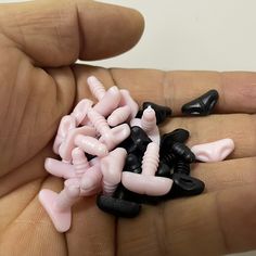 a person holding several small toy figures in their palm, one is pink and the other is black