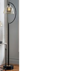 a black and white floor lamp with two glass shades on the base, in front of a gray wall