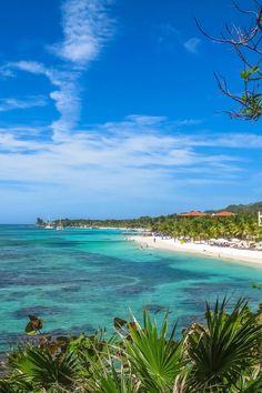 the beach is surrounded by tropical vegetation and blue water