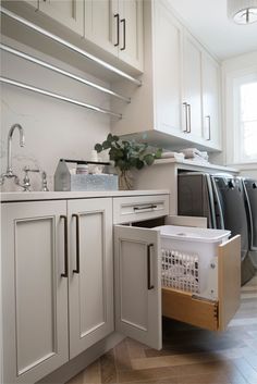 an open dishwasher sitting inside of a kitchen next to a sink and cabinets