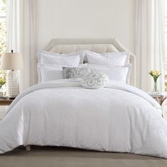 a bed with white linens and pillows in a bedroom