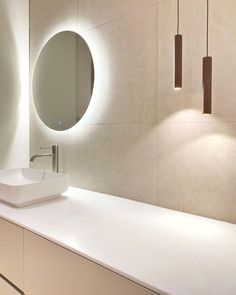 a bathroom with a sink, mirror and lights on the wall above it's counter