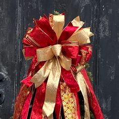 a large red and gold bow on top of a tree in front of a door