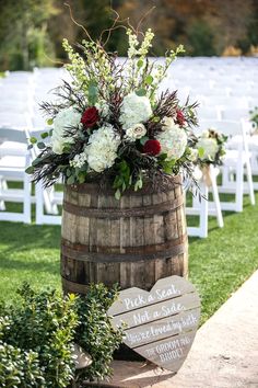 a wooden barrel with flowers in it sitting next to a sign that says tuscany hill wedding ceremony and reception hall