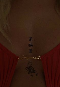 the back of a woman's neck with chinese writing on it and a scorpion tattoo