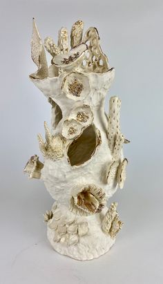 a white vase sitting on top of a table filled with shells and seashells