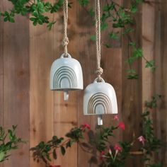 two white bell shaped lights hanging from a wooden fence