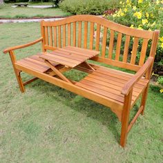 a wooden bench sitting on top of a lush green field next to yellow wildflowers