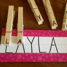 a wooden block with the word laya spelled out on it next to some clothes pins