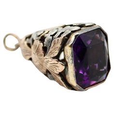 This mixed-metal piece combines 14k rose gold and silver in the beautiful floral and foliate motif of an open work cone. A rose gold flower dangles in silhouette, surrounded by a frame of silver leaves. At the bottom is a deep purple amethyst, emerald cut and bezel set. When looked at head on, the structure of the cone can be seen through the amethyst, giving an infinity effect as the floral motif is reflected kaleidoscopically within the stone. The fob is circa the Arts and Crafts Movement of t Vintage Amethyst Pendant Jewelry, Vintage Amethyst Pendant Necklace, Exquisite Amethyst Pendant Necklace, Ornate Amethyst Pendant Necklaces, Bohemian Amethyst Pendant, Rose Gold Flower, Gold Flowers, Silver Leaf, Hand Engraving