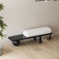 a black and white bench sitting next to a potted plant on top of a hard wood floor