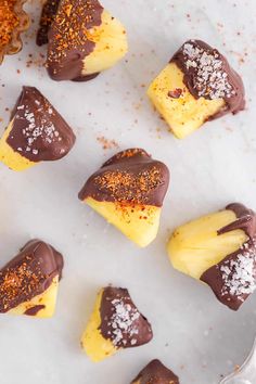 several pieces of chocolate covered dessert sitting on top of a white plate with sprinkles