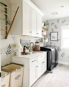 a laundry room with white cabinets and black washer and dryer in the corner