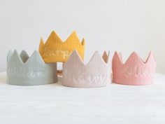 four little crowns with the word mama written on them in white, pink, yellow and blue