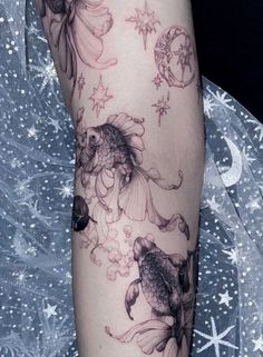 a woman's arm with fish and stars on it