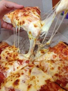 a person taking a slice of pizza from a pan with cheese on it and melted cheese