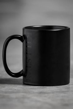 a black coffee mug sitting on top of a table